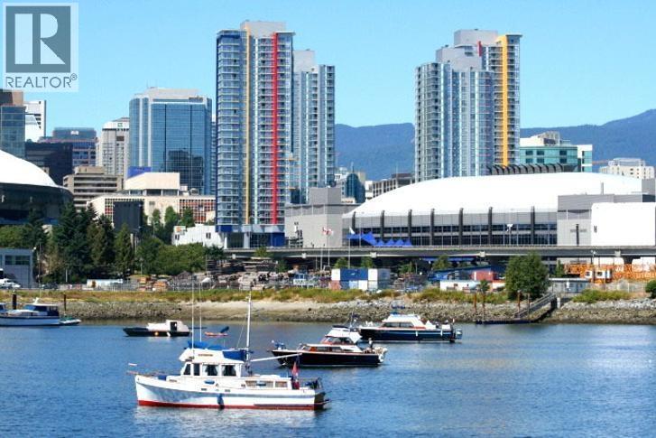 A cityscape with a boat in the foreground and a stadium in the background.