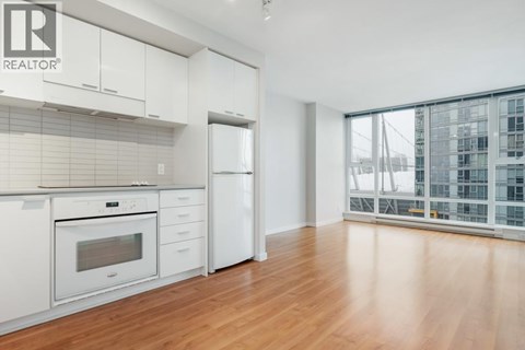 A modern kitchen with white appliances and wooden floors.