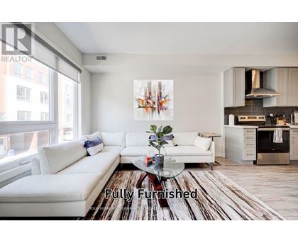 A fully furnished living room with a white couch and a wooden floor.