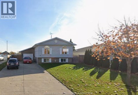 A house with a driveway and a tree with orange leaves.
