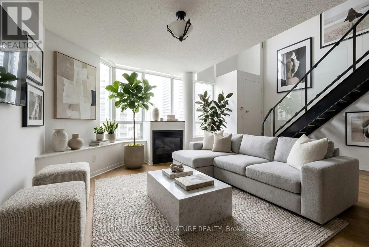 A living room with a grey couch, a coffee table, and a staircase.