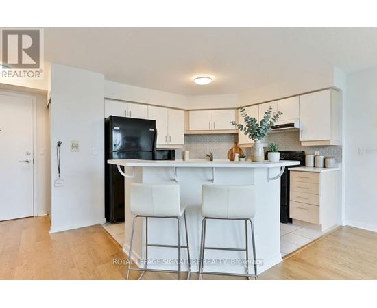 A kitchen with white cabinets and a black fridge.