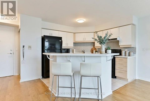A kitchen with white cabinets and a black fridge.