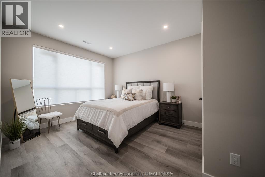 A bedroom with a large bed, a chair, and a nightstand with a lamp.