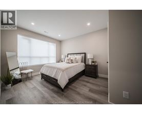 A bedroom with a large bed, a chair, and a nightstand with a lamp.