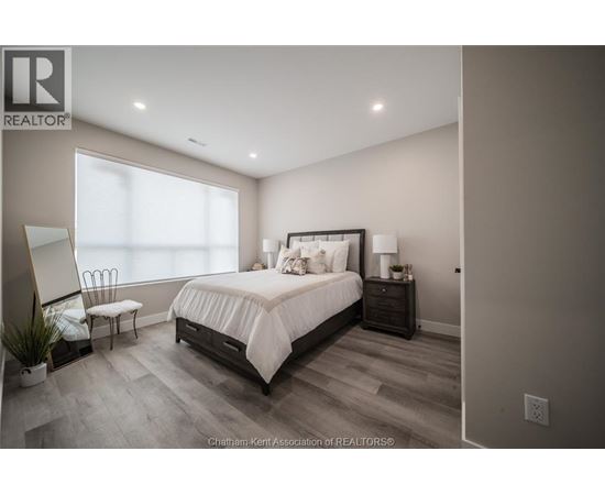 A bedroom with a large bed, a chair, and a nightstand with a lamp.