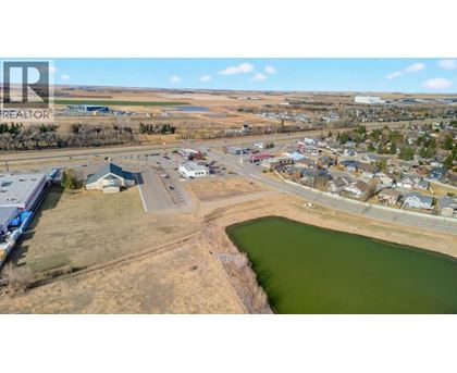 A small town with a lake in the foreground and a realtor logo in the corner.