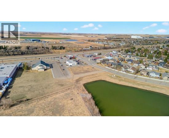 A small town with a lake in the foreground and a realtor logo in the corner.