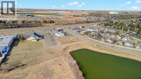 A small town with a lake in the foreground and a realtor logo in the corner.