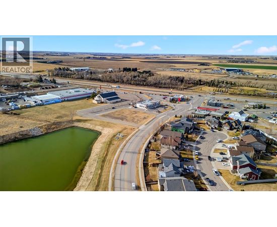 A bird's eye view of a small town with a lake and a road curving around it.