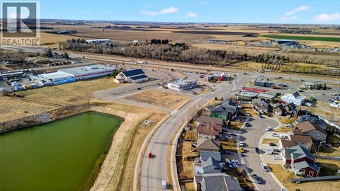 A bird's eye view of a small town with a lake and a road curving around it.