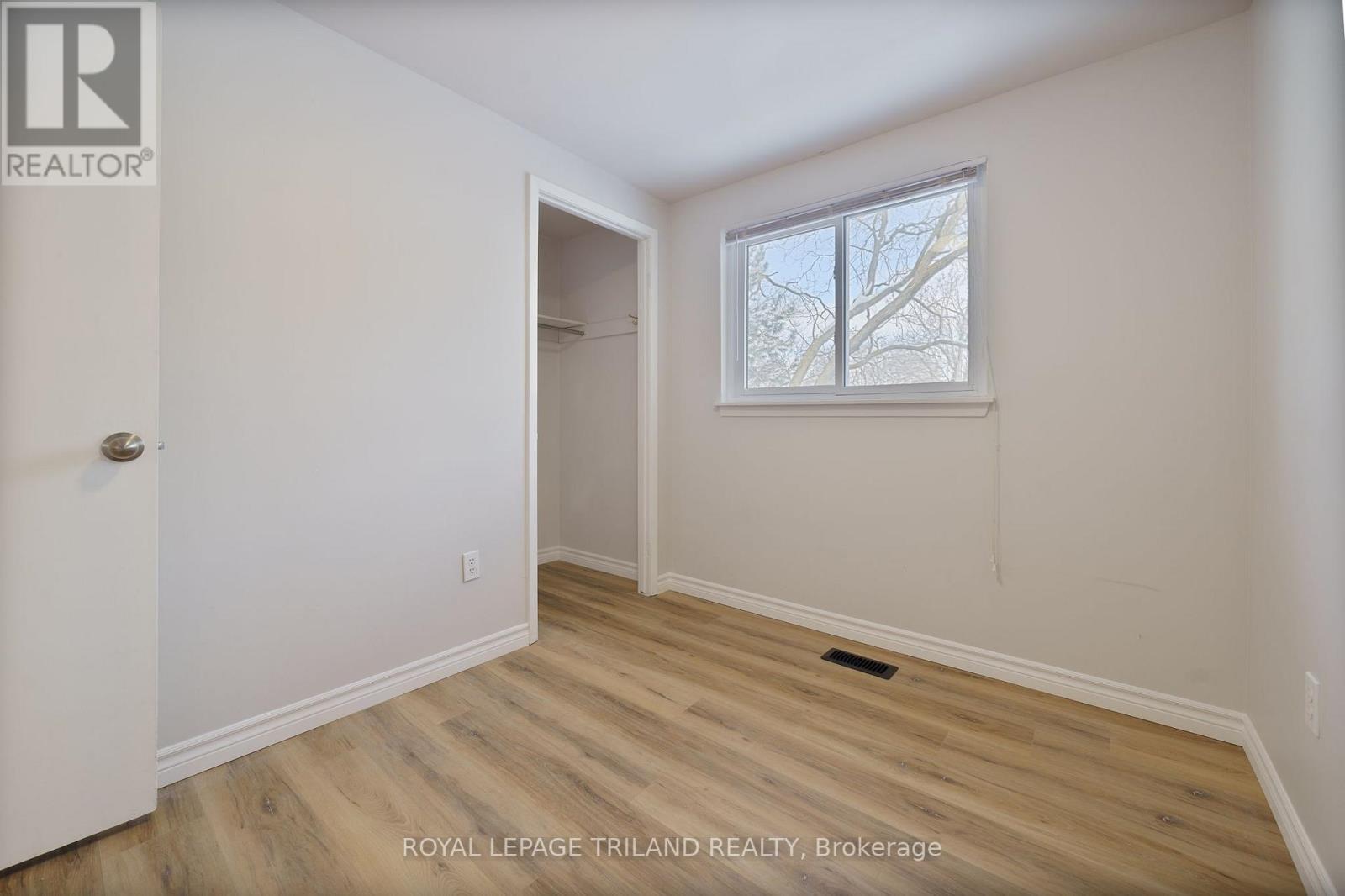 A room with a door and a window with a view of trees.