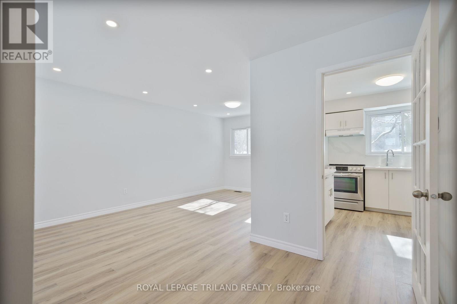 A spacious room with wooden flooring and white walls.