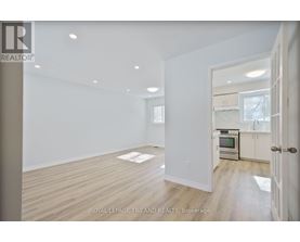 A spacious room with wooden flooring and white walls.