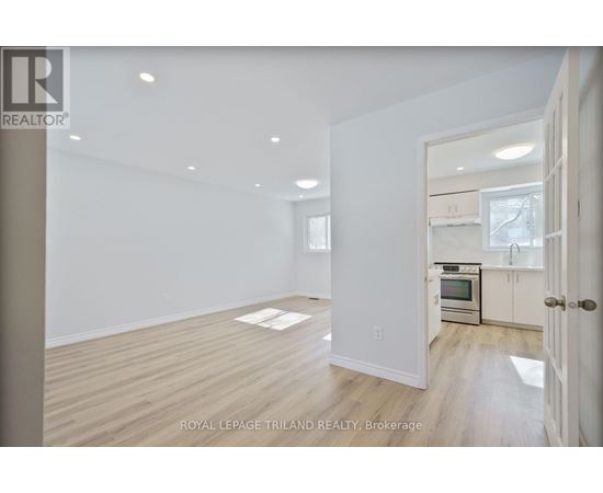 A spacious room with wooden flooring and white walls.