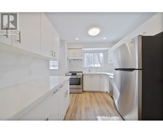 A modern kitchen with white cabinets and a stainless steel refrigerator.