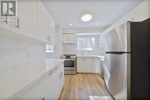 A modern kitchen with white cabinets and a stainless steel refrigerator.
