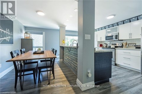 A kitchen with a dining table and chairs in the foreground and a kitchen in the background.