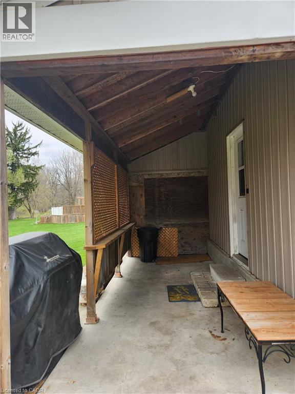 A covered porch area with a bench and a grill.