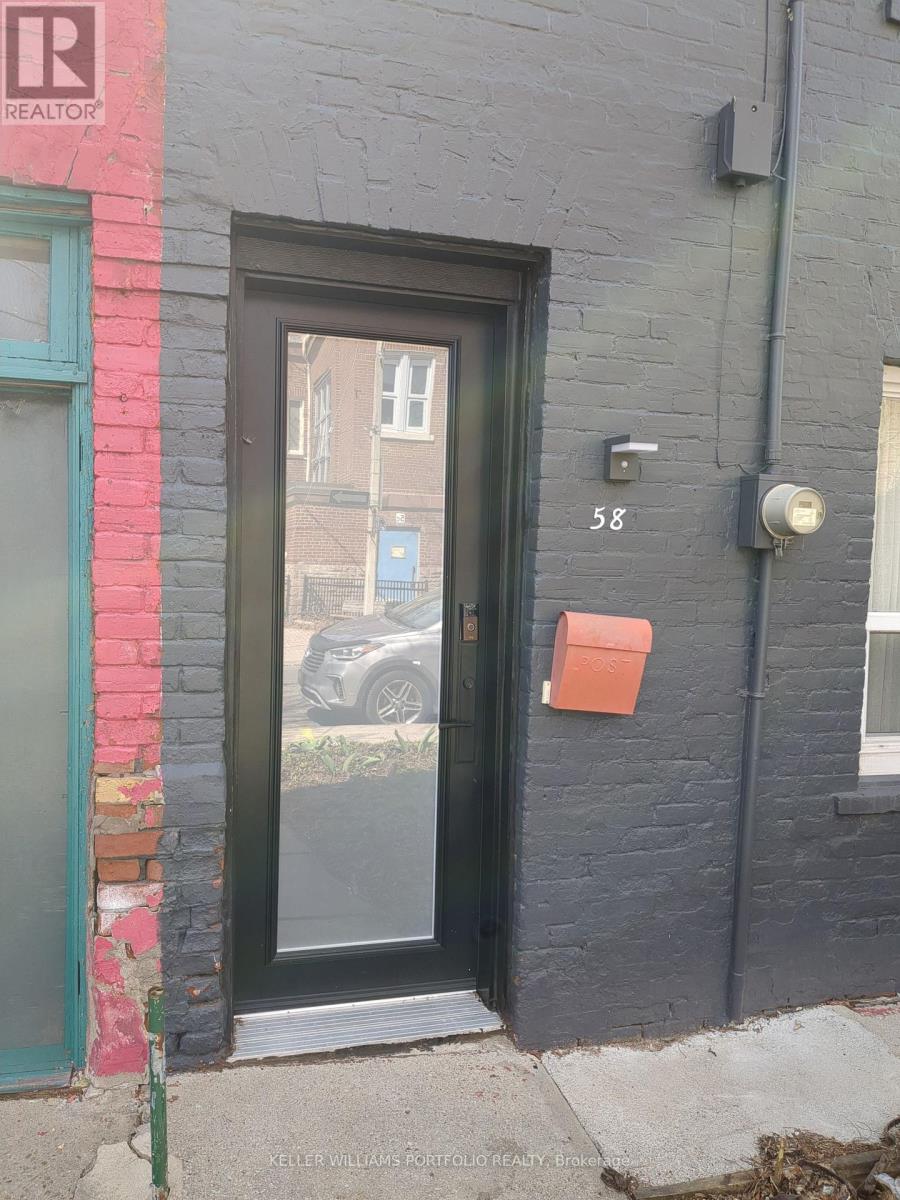 A black door with a glass window and a red box on the wall.
