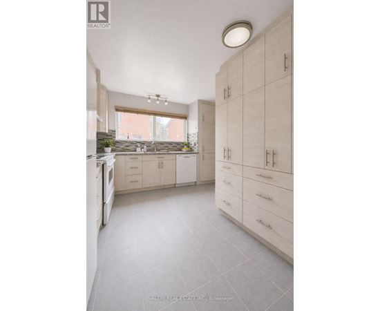A kitchen with white cabinets and a window.