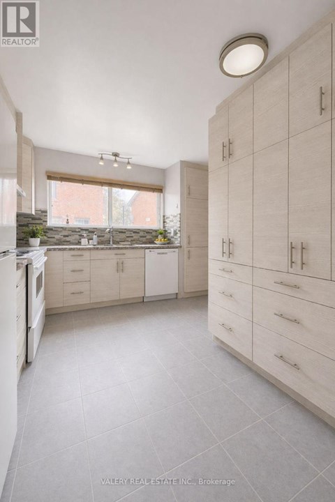 A kitchen with white cabinets and a window.