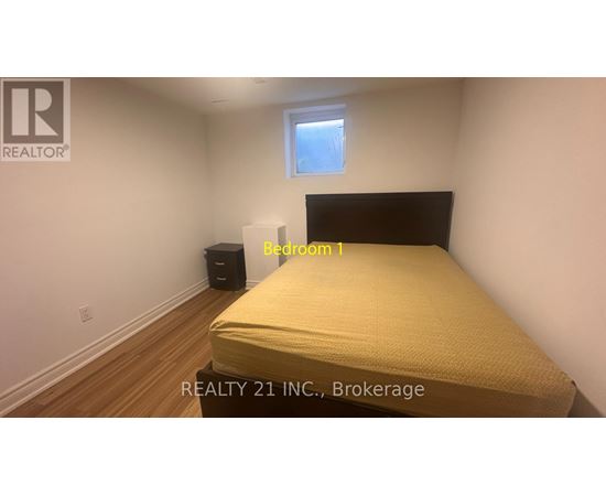 A bedroom with a bed, a window, and a trash can.