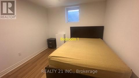 A bedroom with a bed, a window, and a trash can.