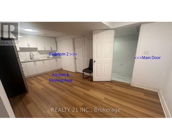 A room with a kitchen and dining area with a black fridge and a white door.