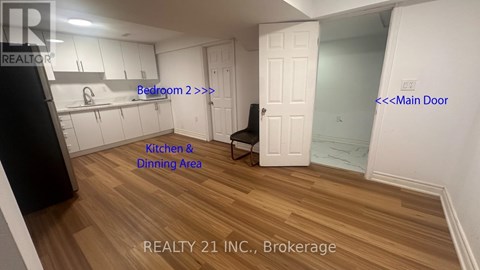 A room with a kitchen and dining area with a black fridge and a white door.