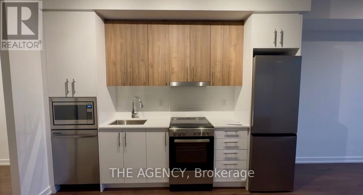 A kitchen with a stainless steel refrigerator, microwave, and oven.