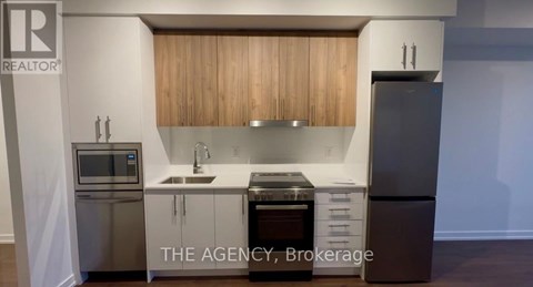 A kitchen with a stainless steel refrigerator, microwave, and oven.