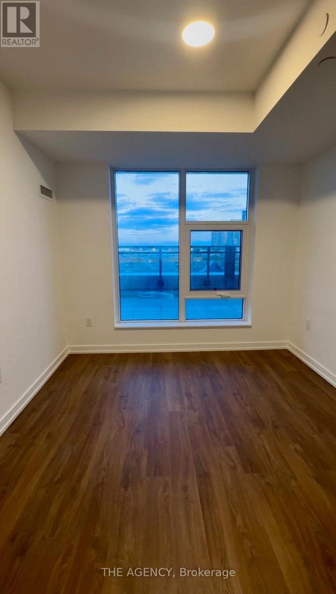 A room with wooden floors and a window overlooking a body of water.