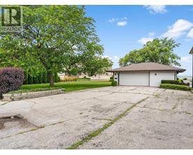 A large, empty driveway leads to a garage with a house in the background.