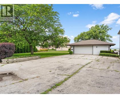 A large, empty driveway leads to a garage with a house in the background.