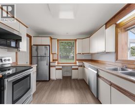 A kitchen with a stove top oven, refrigerator, and a window.