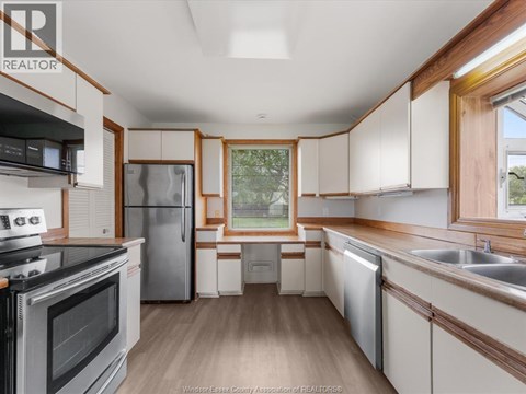 A kitchen with a stove top oven, refrigerator, and a window.