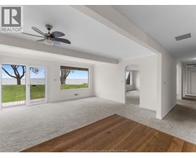 A spacious room with a ceiling fan and sliding glass doors leading to a grassy area.