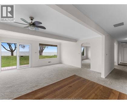 A spacious room with a ceiling fan and sliding glass doors leading to a grassy area.