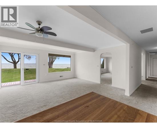 A spacious room with a ceiling fan and sliding glass doors leading to a grassy area.