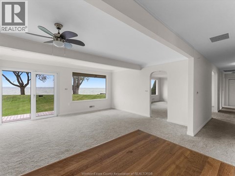 A spacious room with a ceiling fan and sliding glass doors leading to a grassy area.