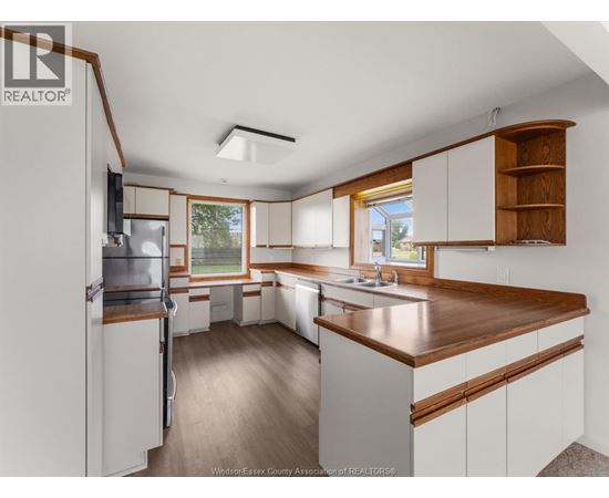 A kitchen with white cabinets and a wooden counter top.