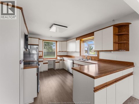 A kitchen with white cabinets and a wooden counter top.