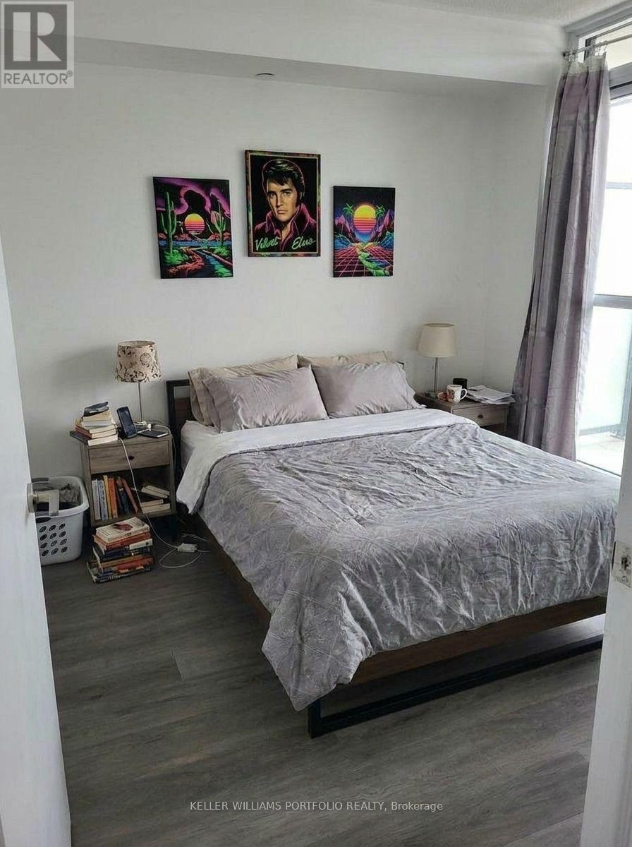 A bedroom with a bed, nightstands, and two colorful paintings on the wall.