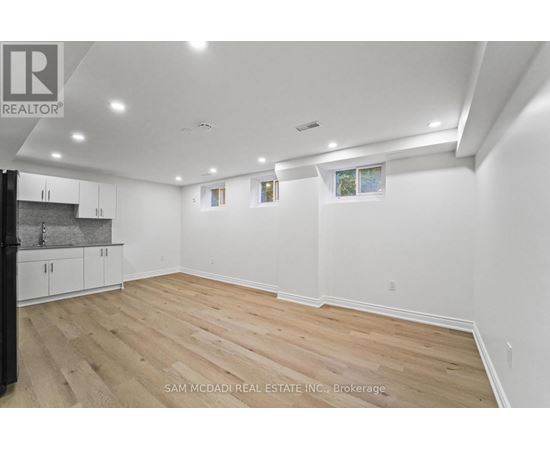 A spacious room with wooden flooring and white walls.