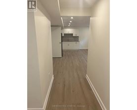 A hallway with wood flooring and white walls.