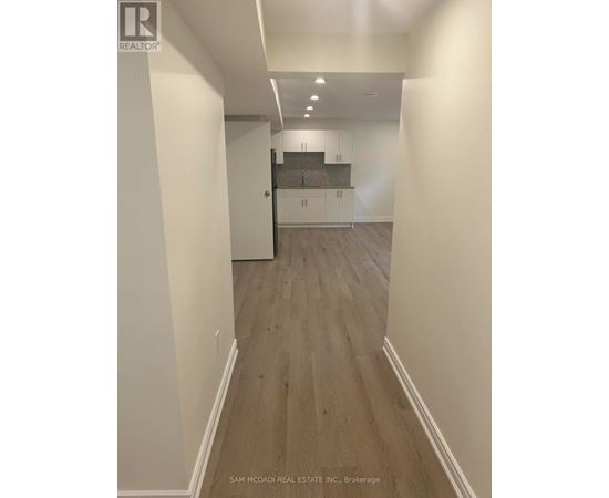 A hallway with wood flooring and white walls.