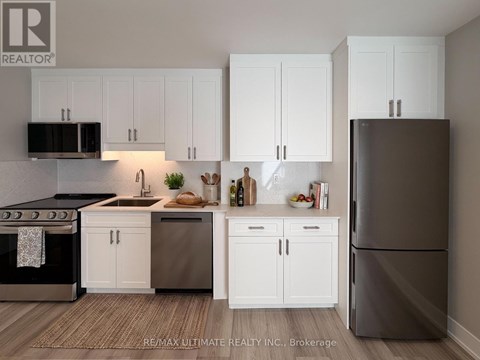 A kitchen with white cabinets and a black refrigerator.