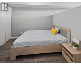A bedroom with a bed, nightstand, and a plant on the nightstand.