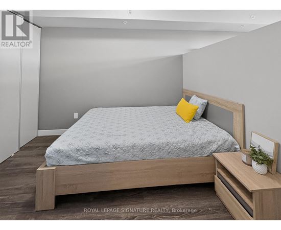 A bedroom with a bed, nightstand, and a plant on the nightstand.